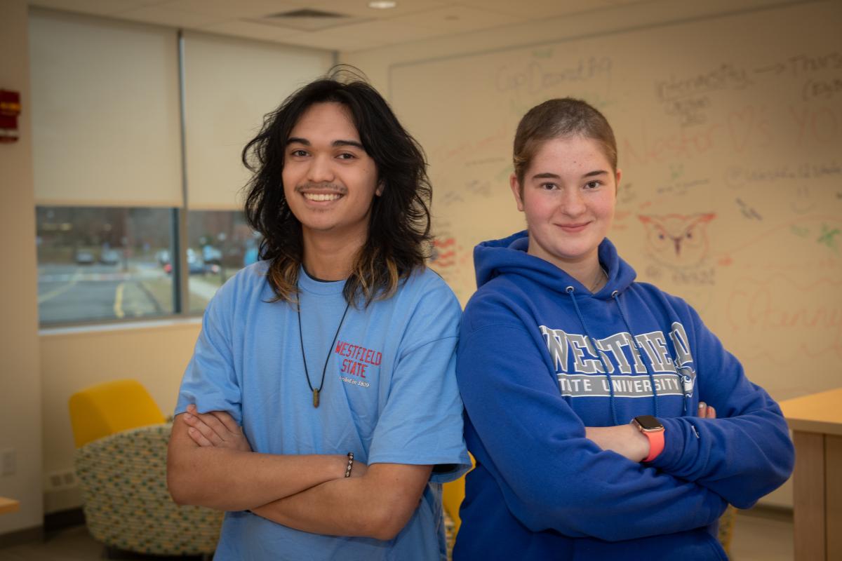 Two students back to back wearing WSU shorts with arms crossed smiling.