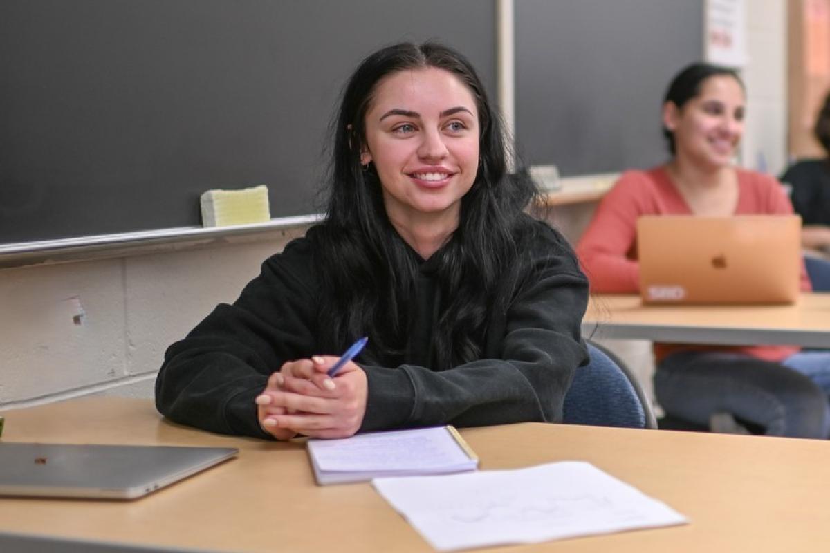 ABA student smiling in a classroom holding a pen.