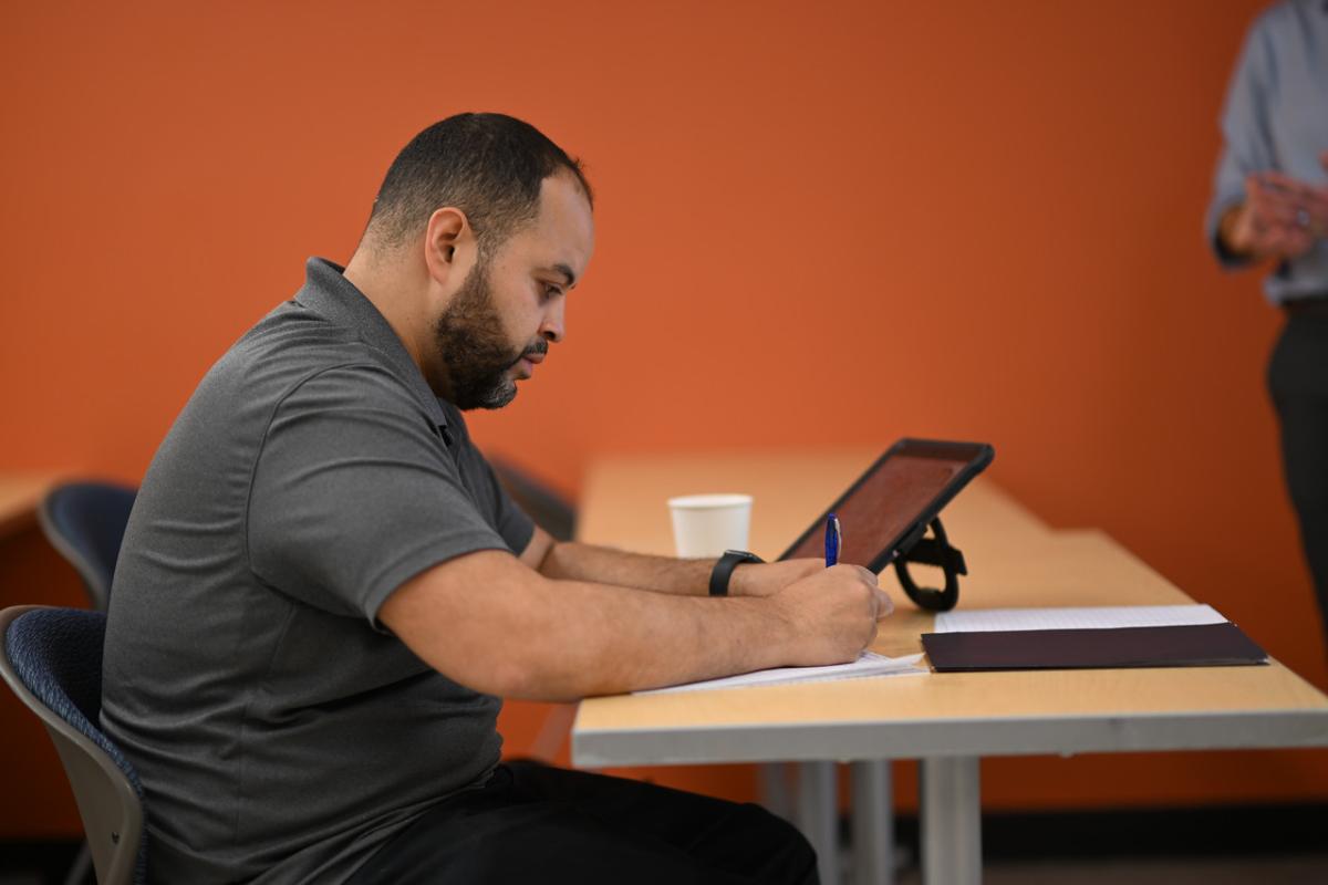 Psychology student writing on a piece of paper with laptop on desk.