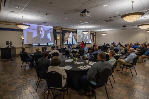 Attendees sit around tables as they listen to the speaker present on hate-crimes.