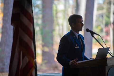 Colonel David Halasi-Kun stands next to an American flag while he addresses attendees for the 2023 Veteran's Day Ceremony.