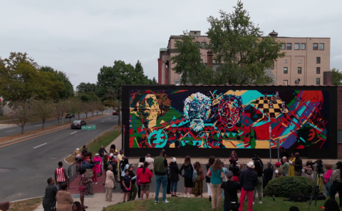 A crowd gathers outside a mural by AfriCOBRA raist and muralist Nelson Stevens in the documentary "Art for the People," directed by Evan Goodchild. Credits to Evan Goodchild and Goodchild Media.