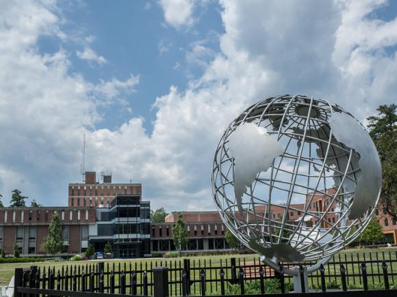 The globe sculpture on the campus green with the Ely Campus Center in the background