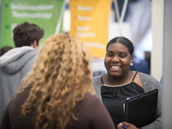 Smiling female talks with a prospective employer at the Career Fair