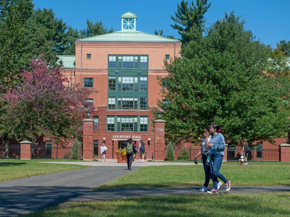 Image of two students walking on the campus green in front of Courtney Hall