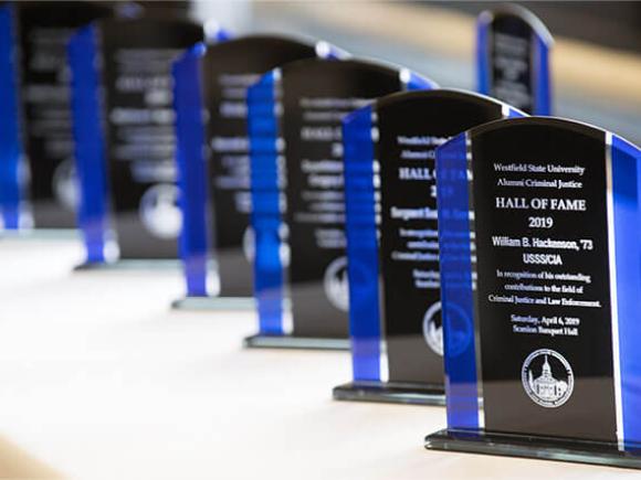 A line of Westfield State University Alumni Criminal Justice Hall of Fame awards arranged on a table.