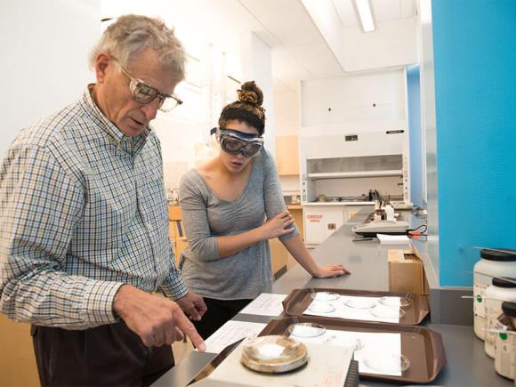 A professor discusses lab work with a student in a laboratory setting.