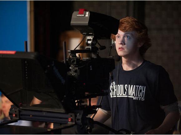 A student operates a professional video camera in a student setting.