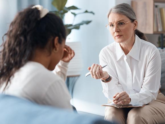 A counselor talks with a patient sitting across from them.