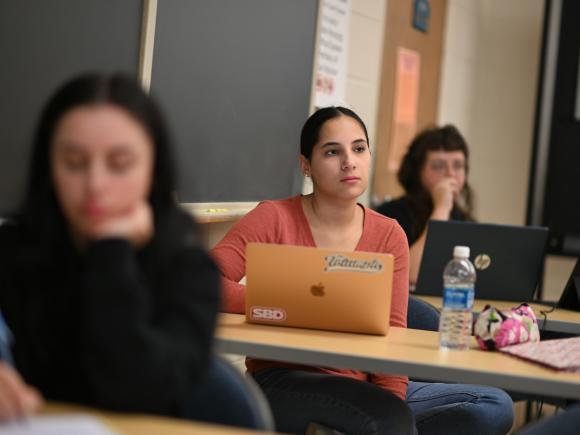 Psychology graduate student in classroom with laptop.