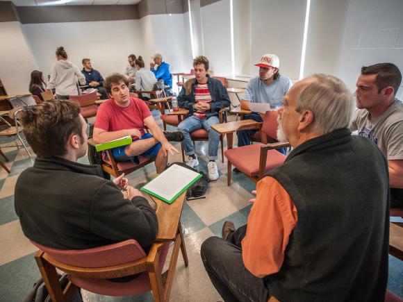 Faculty member speaking with students in a small group.