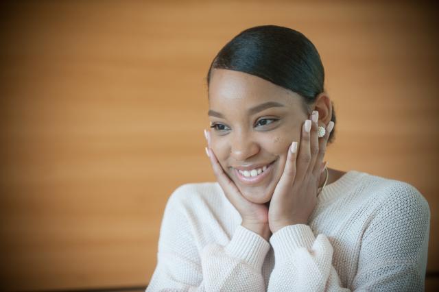 female student smiles as her hands cradle her face