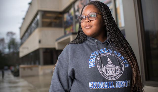 A student poses for a photo while wearing a sweatshirt that says “Westfield State Criminal Justice.”