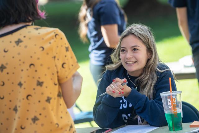 Student on campus drinking Dunkin coffee at picnic table