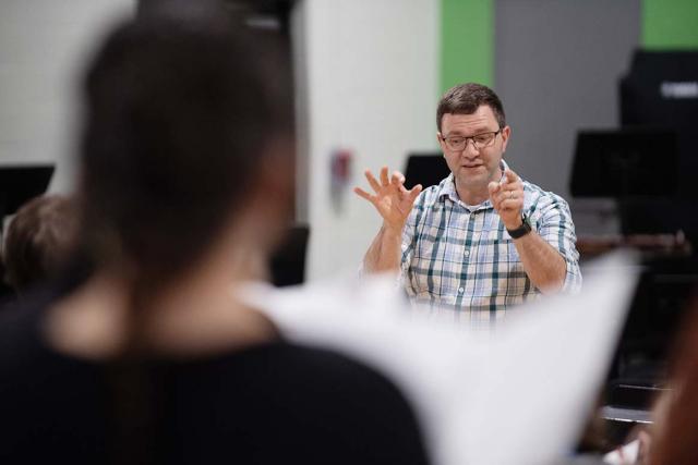 A Westfield State University music professor conducts students in a music classroom.