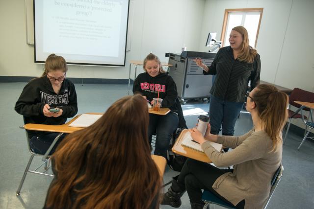 Sociology class with a professor speaking with a small group of students.