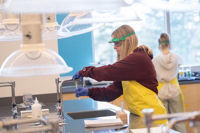 Student filling a test tube at a sink in a lab.