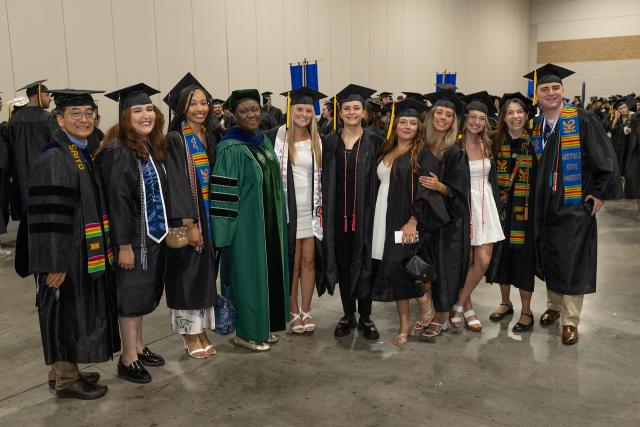 Communication students and faculty smiling at commencement.