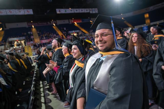 Smiling graduate students celebrating at commencement.